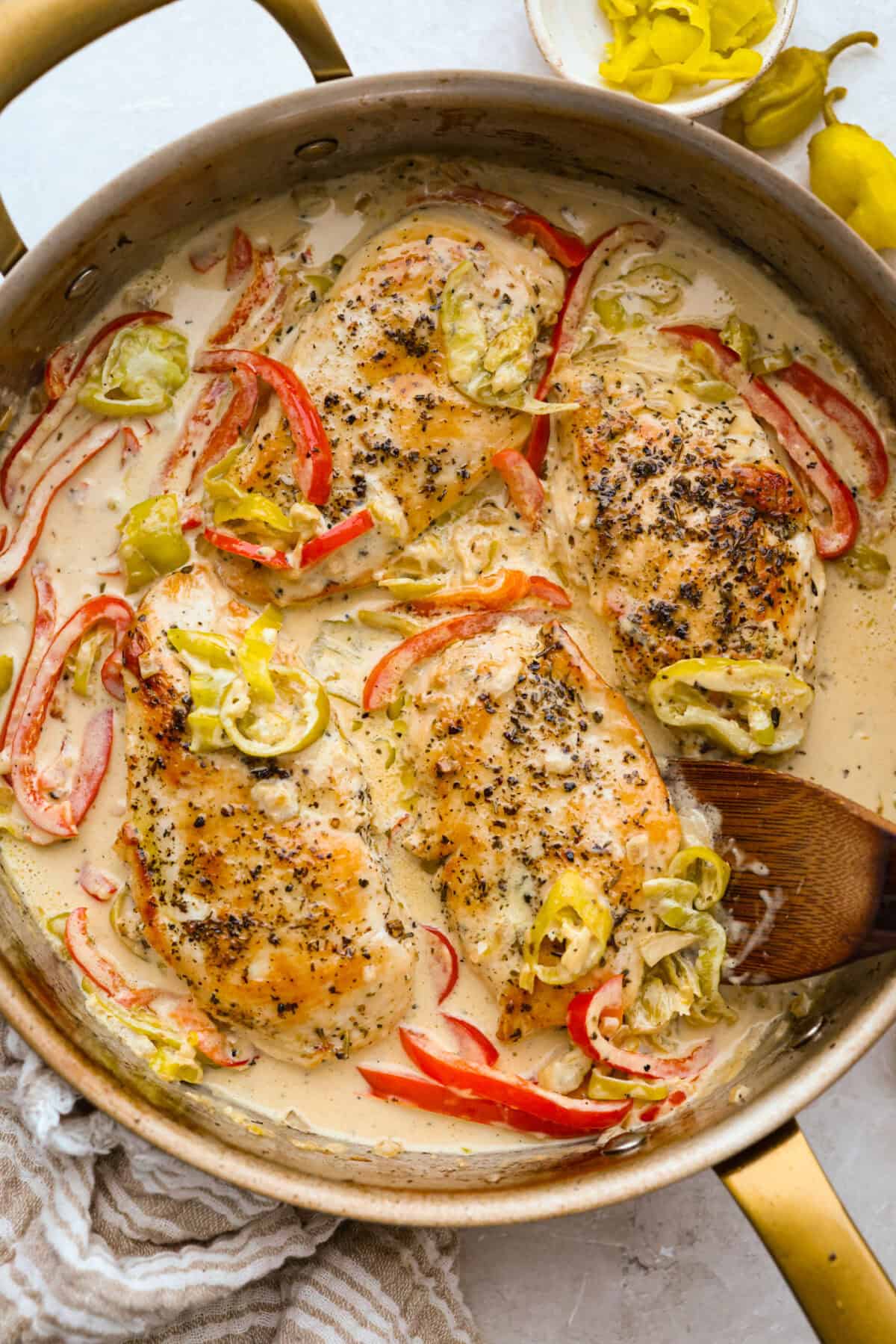 Creamy pepperoncini chicken is an easy one-skillet dinner packed with flavor! Tender chicken is smothered in a rich Parmesan cream sauce with bell peppers and tangy pepperoncini. It's the perfect balance of creamy, savory, and zesty flavor. Skillet with creamy pepperoncini chicken in it.