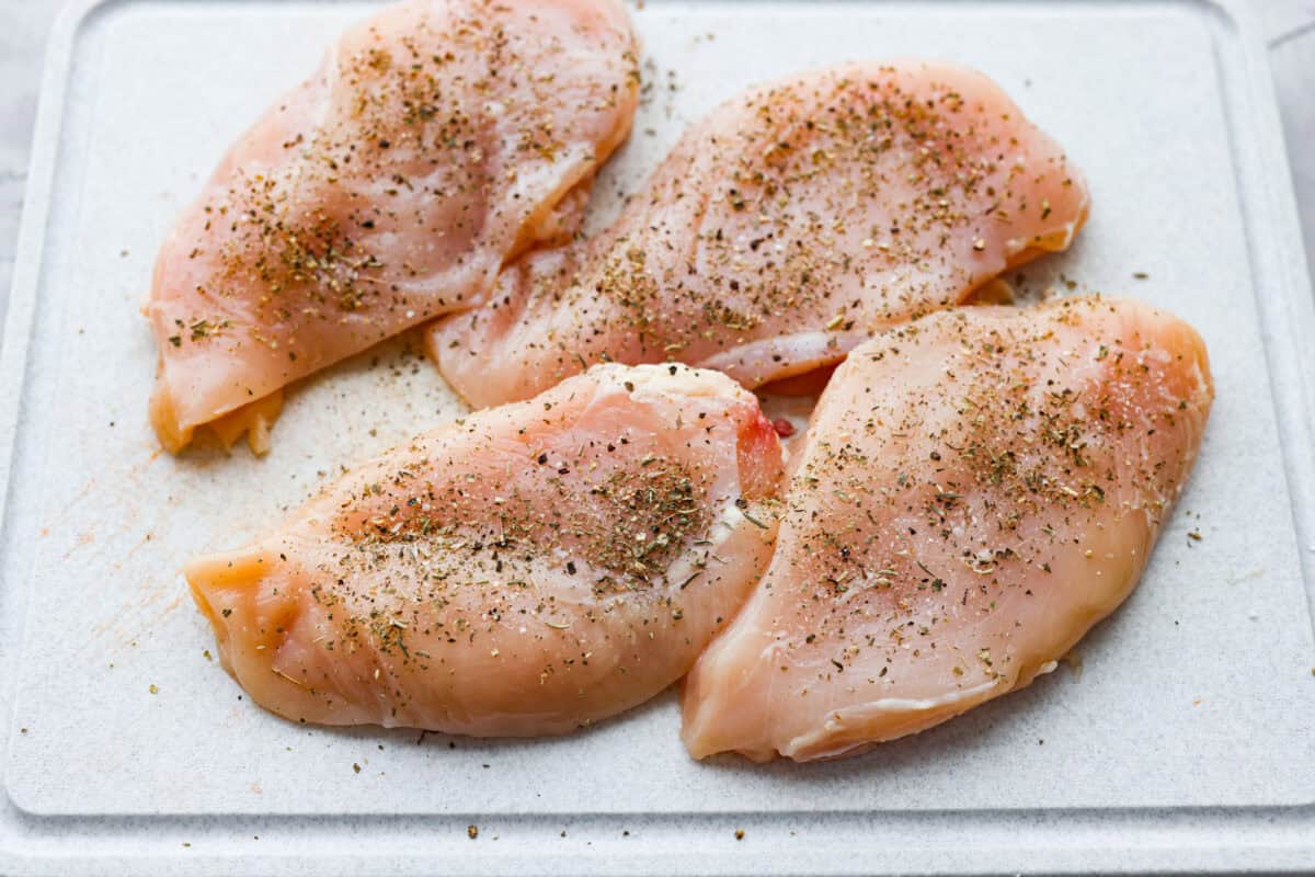 Creamy pepperoncini chicken is an easy one-skillet dinner packed with flavor! Tender chicken is smothered in a rich Parmesan cream sauce with bell peppers and tangy pepperoncini. It's the perfect balance of creamy, savory, and zesty flavor. Chicken breasts on a cutting board and seasoned.