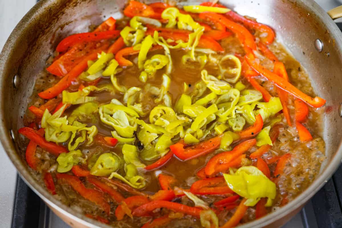 Creamy pepperoncini chicken is an easy one-skillet dinner packed with flavor! Tender chicken is smothered in a rich Parmesan cream sauce with bell peppers and tangy pepperoncini. It's the perfect balance of creamy, savory, and zesty flavor. Pepperoncini's cooking in a skillet with the peppers and chicken broth.