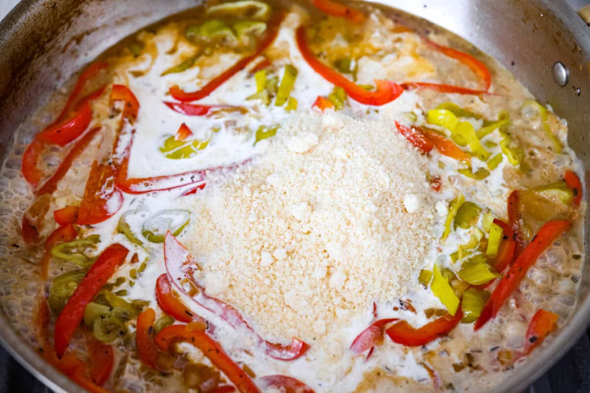 Creamy pepperoncini chicken is an easy one-skillet dinner packed with flavor! Tender chicken is smothered in a rich Parmesan cream sauce with bell peppers and tangy pepperoncini. It's the perfect balance of creamy, savory, and zesty flavor. Parmesan cheese and cream added to the skillet to make the creamy pepperoncini chicken sauce.