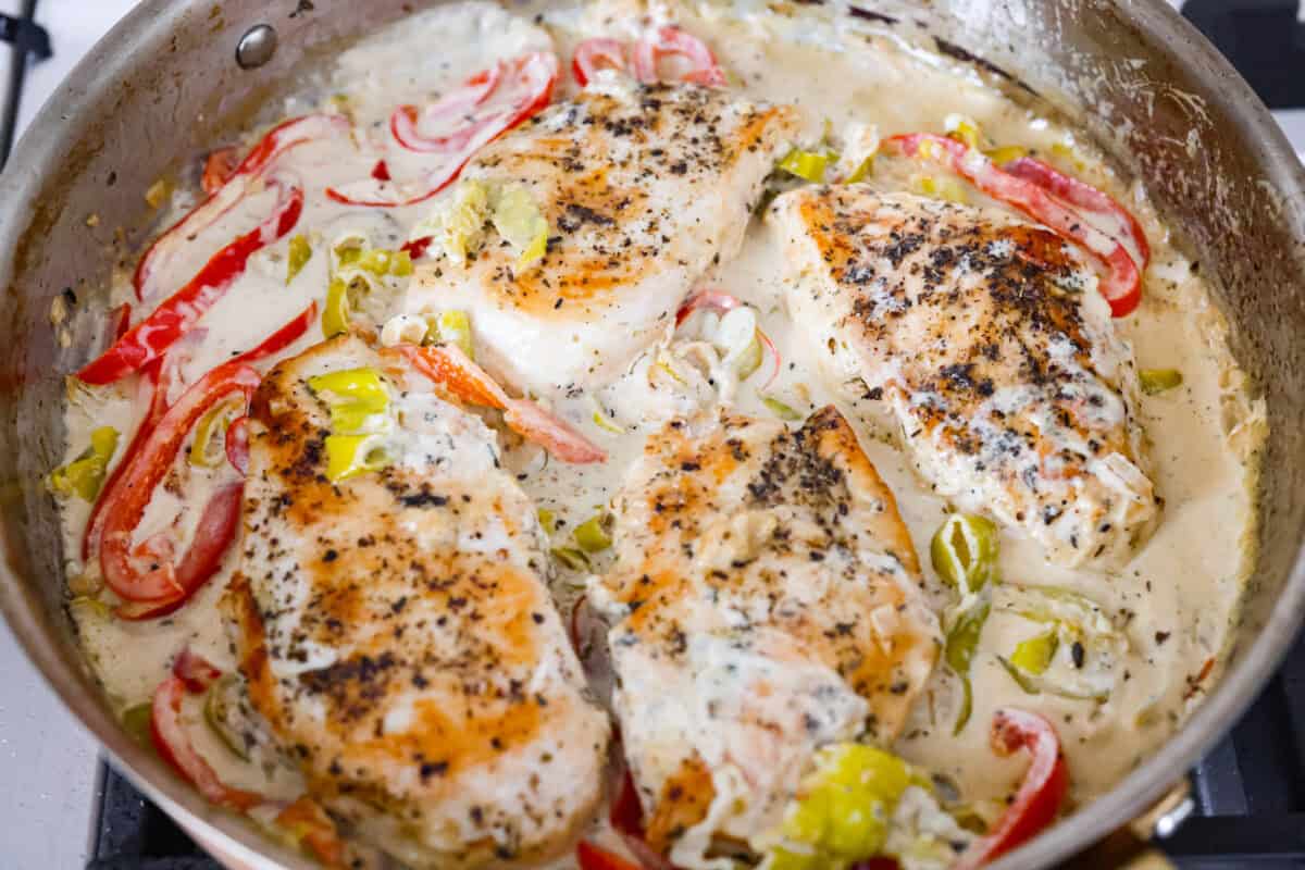 Creamy pepperoncini chicken is an easy one-skillet dinner packed with flavor! Tender chicken is smothered in a rich Parmesan cream sauce with bell peppers and tangy pepperoncini. It's the perfect balance of creamy, savory, and zesty flavor. Cooked chicken breasts added back to the skillet to cook in the creamy pepperoncini chicken sauce.