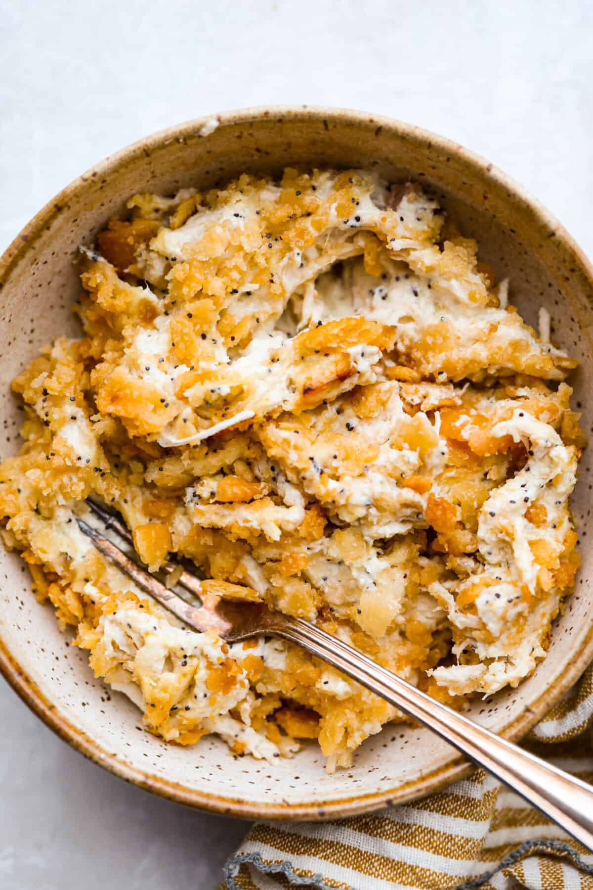 Poppy seed chicken casserole is creamy, cozy, and so easy to make! Tender chicken is topped with buttery Ritz crackers for the perfect crunch, and it’s ready in just 35 minutes. Serving of poppy seed chicken casserole in a bowl.