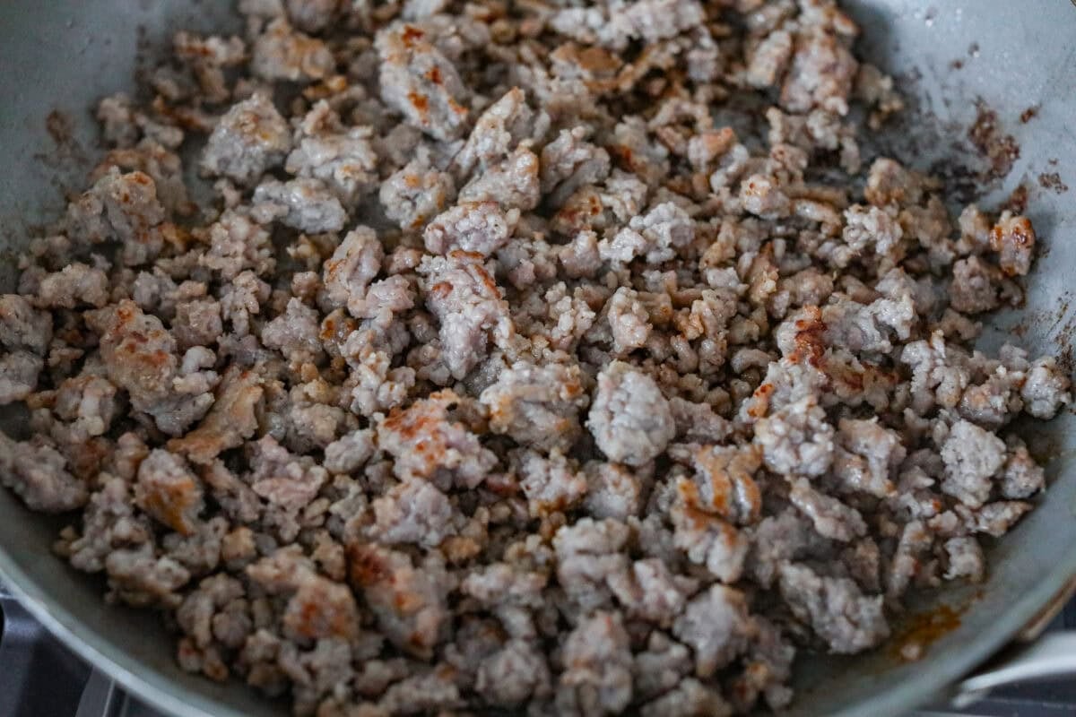 Sausage being browned in a skillet. 