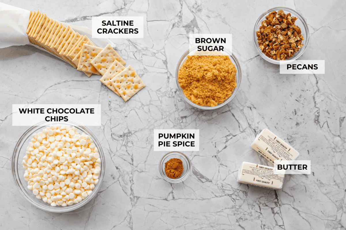 Pumpkin spice crack is Christmas crack with a fall twist! Buttery toffee, salty crackers, white chocolate, pumpkin pie spice, and crunchy praline pecans make this an easy treat you won’t be able to stop snacking on. Overhead shot of labeled pumpkin pie spice ingredients.