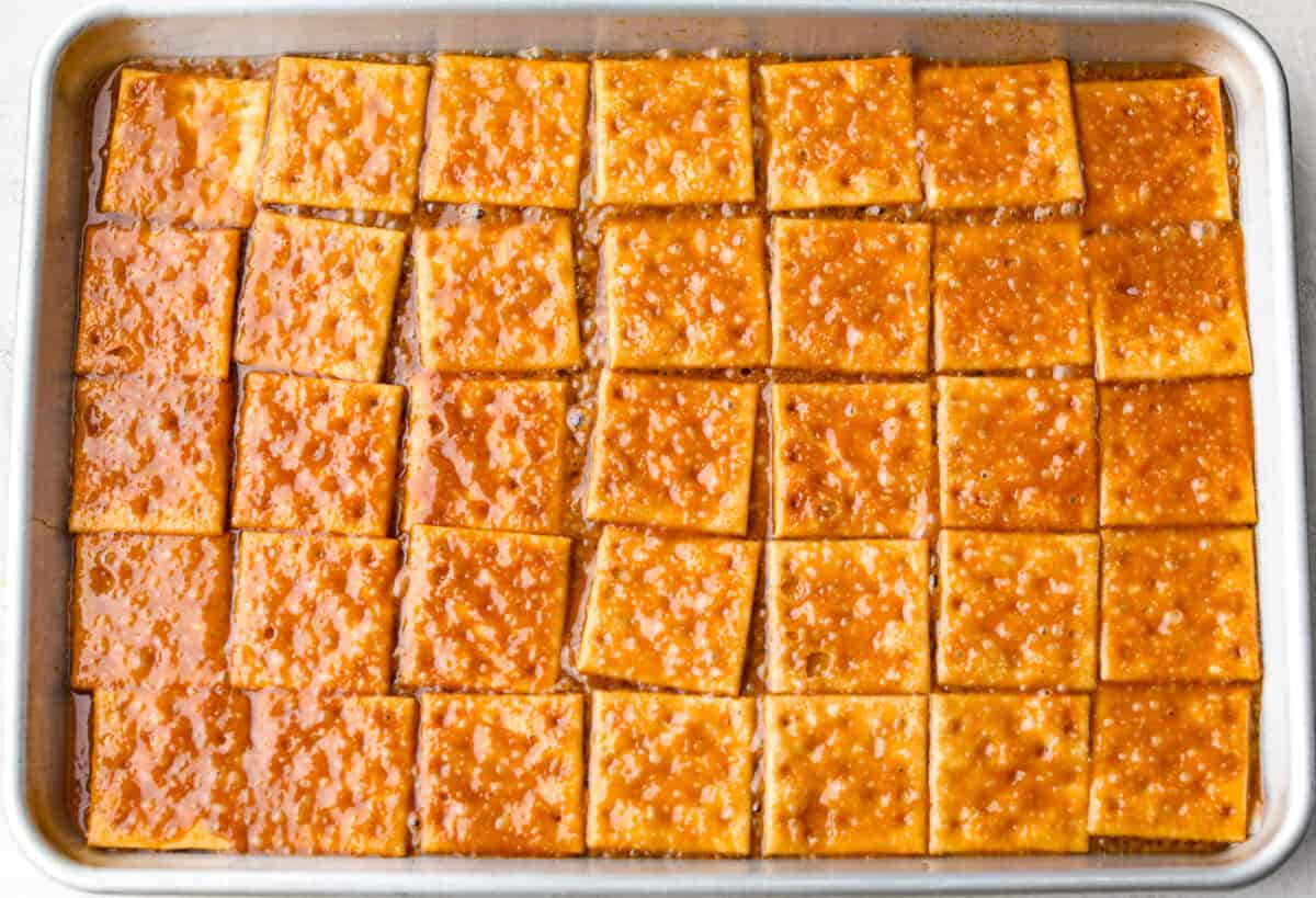 Pumpkin spice crack is Christmas crack with a fall twist! Buttery toffee, salty crackers, white chocolate, pumpkin pie spice, and crunchy praline pecans make this an easy treat you won’t be able to stop snacking on. Toffee spread over the saltine crackers.