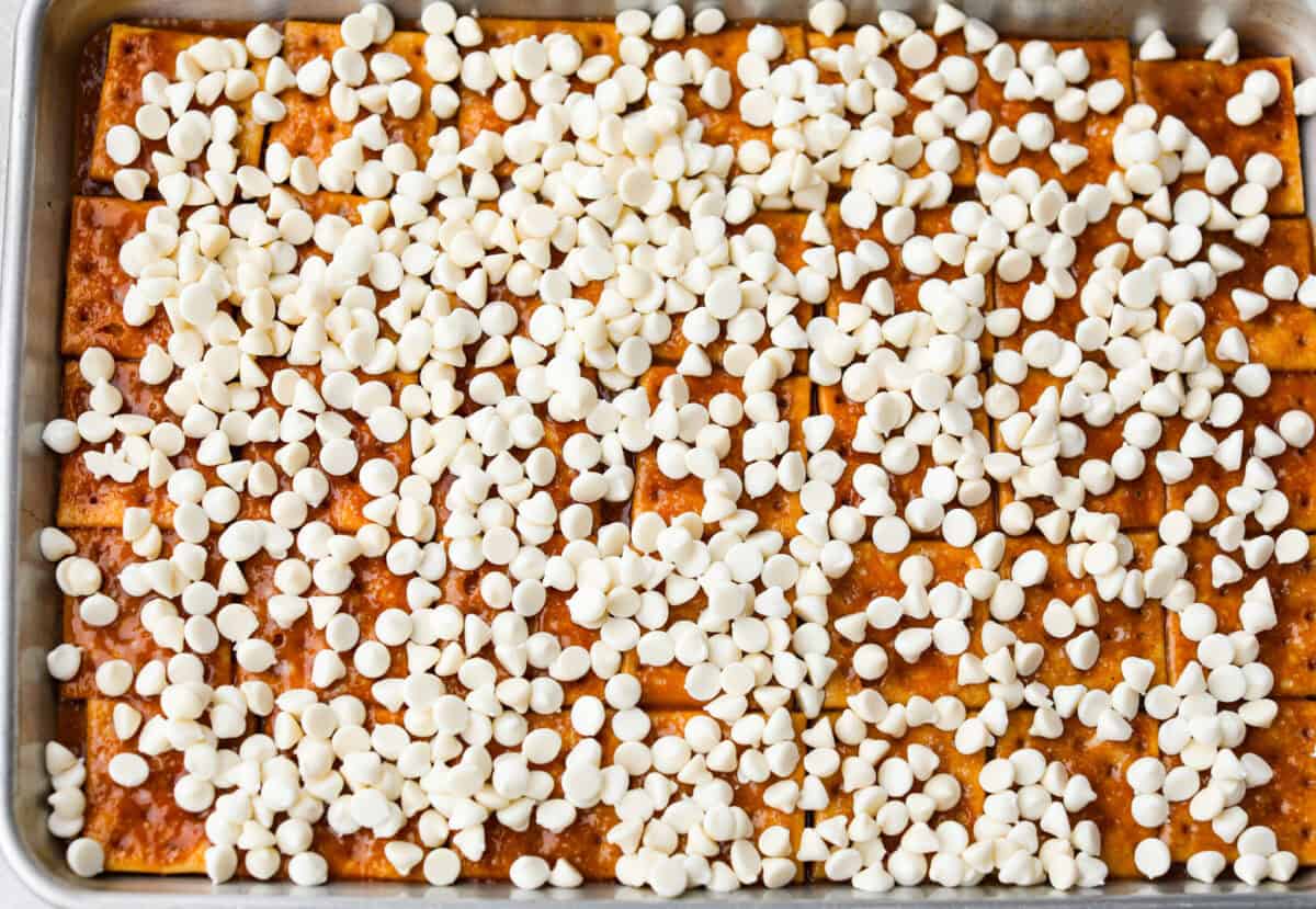 Pumpkin spice crack is Christmas crack with a fall twist! Buttery toffee, salty crackers, white chocolate, pumpkin pie spice, and crunchy praline pecans make this an easy treat you won’t be able to stop snacking on. White chocolate chip wafers sprinkled over the top of the toffee and crackers.