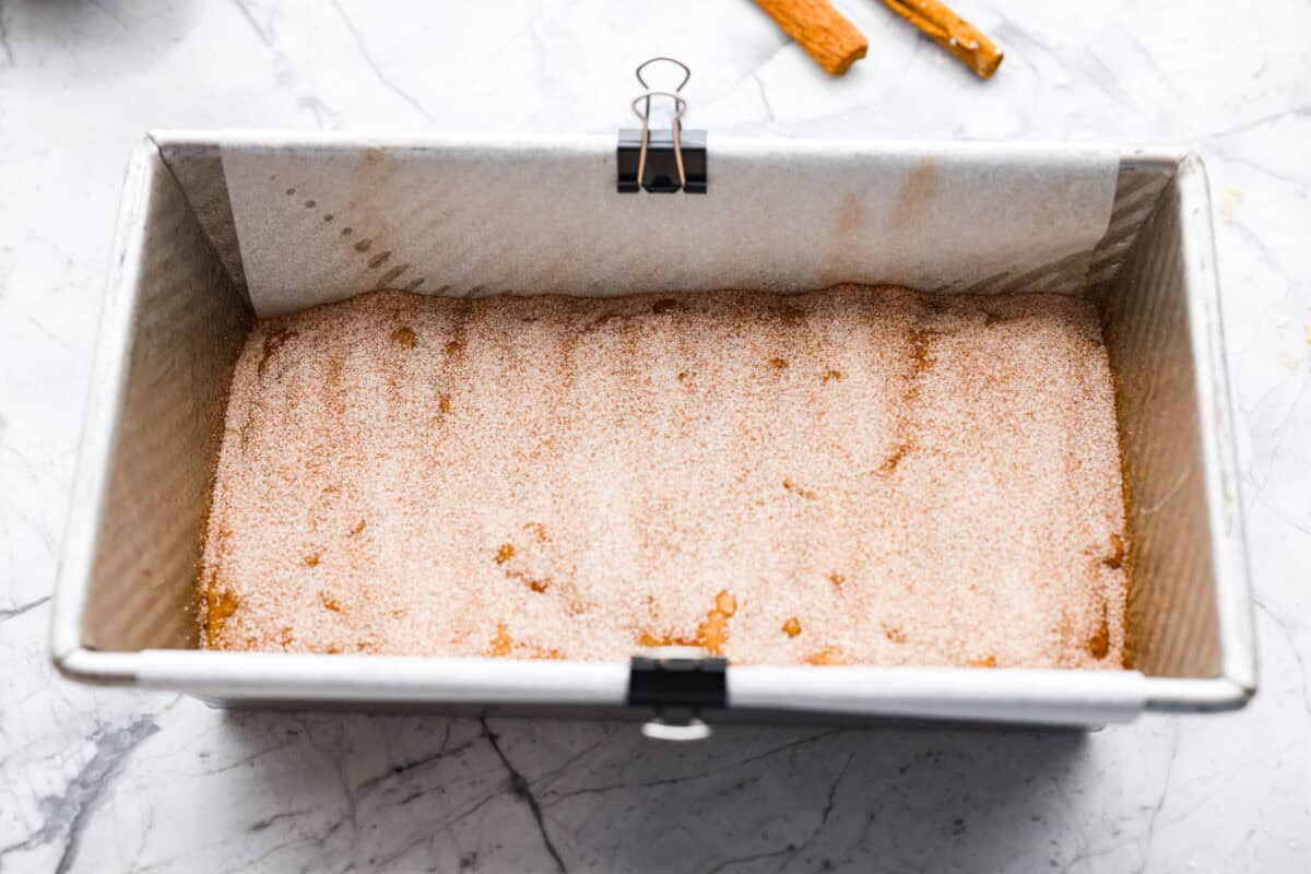 This snickerdoodle donut loaf is a fun twist on the classic cookie! It’s soft, tender, and packed with cinnamon sugar flavor, then finished with a sweet vanilla glaze. Think snickerdoodle meets cake donut in an easy-to-slice loaf! Half of the loaf batter added to a loaf pan, then sprinkled with cinnamon and sugar.
