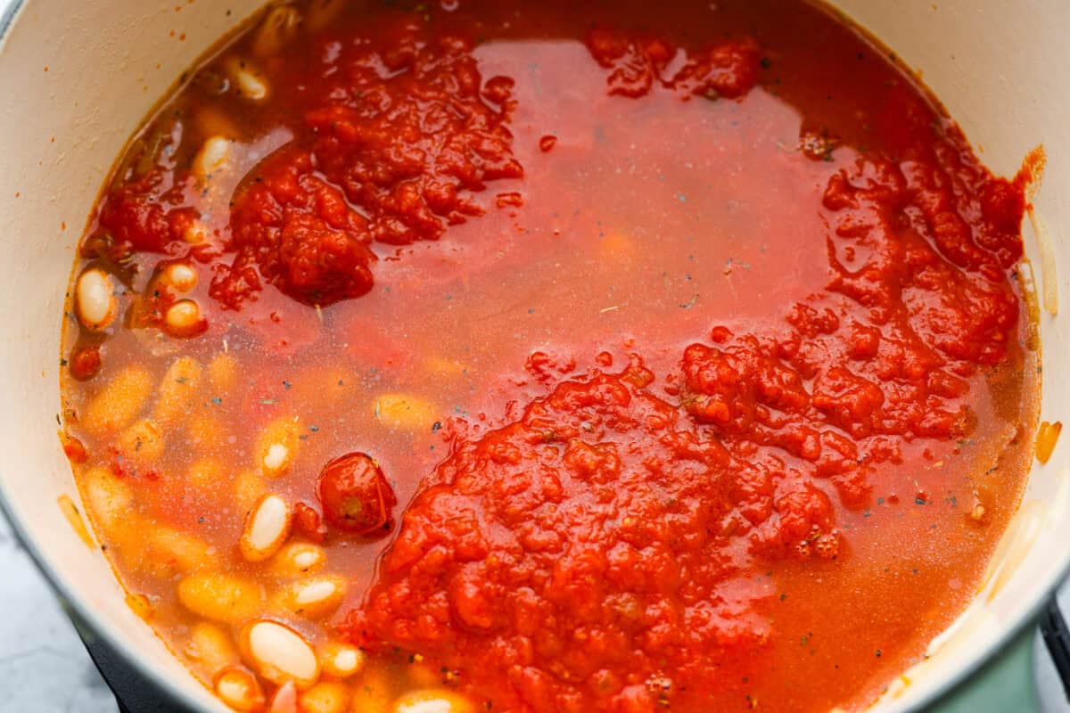I had to try Stanley Tucci’s pasta fagioli, and his shortcut is so smart! He uses marinara sauce to add tons of flavor without a long list of ingredients. Add creamy beans, tender pasta, kale, and Parmesan, and you have a cozy dinner in just 35 minutes. Beans, marinara sauce, and chicken broth added to the pot.