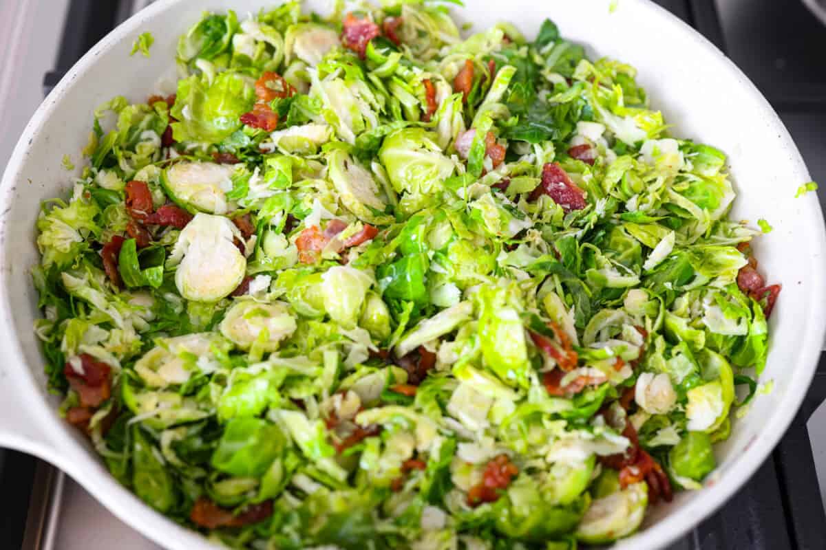 I didn’t always get excited about Brussels sprouts, but this Brussels sprouts salad with bacon changed that. Crispy bacon, tart cranberries, toasted almonds, and Parmesan make every bite so good, with a warm maple-orange dressing to tie it all together. Brussels sprouts, bacon bits, and almonds cooking in the same skillet.
