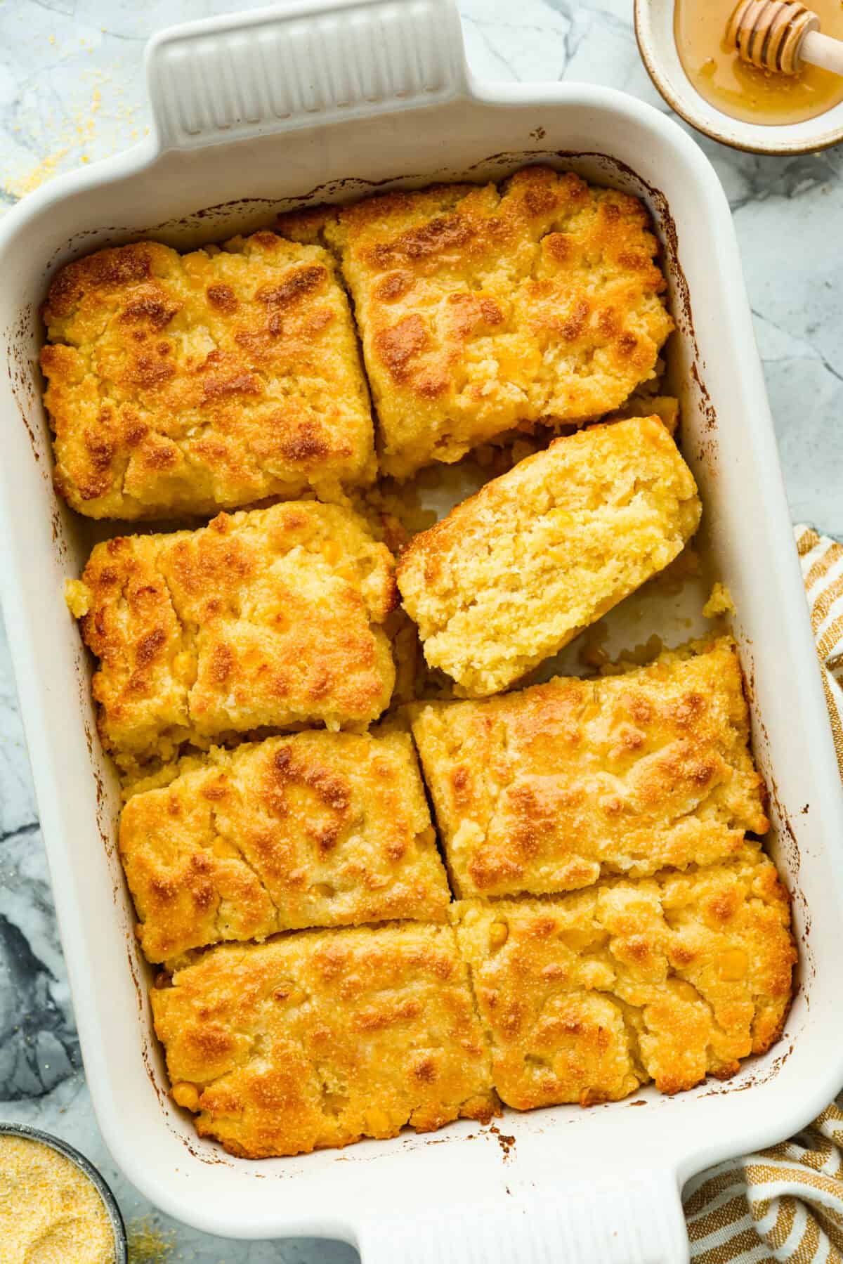Butter swim cornbread bakes in a whole stick of butter for crisp, golden edges and a soft, tender center. My secret ingredient is a can of creamed corn, which makes it extra moist and adds even more sweet corn flavor. overhead shot of baked butter swim cornbread.