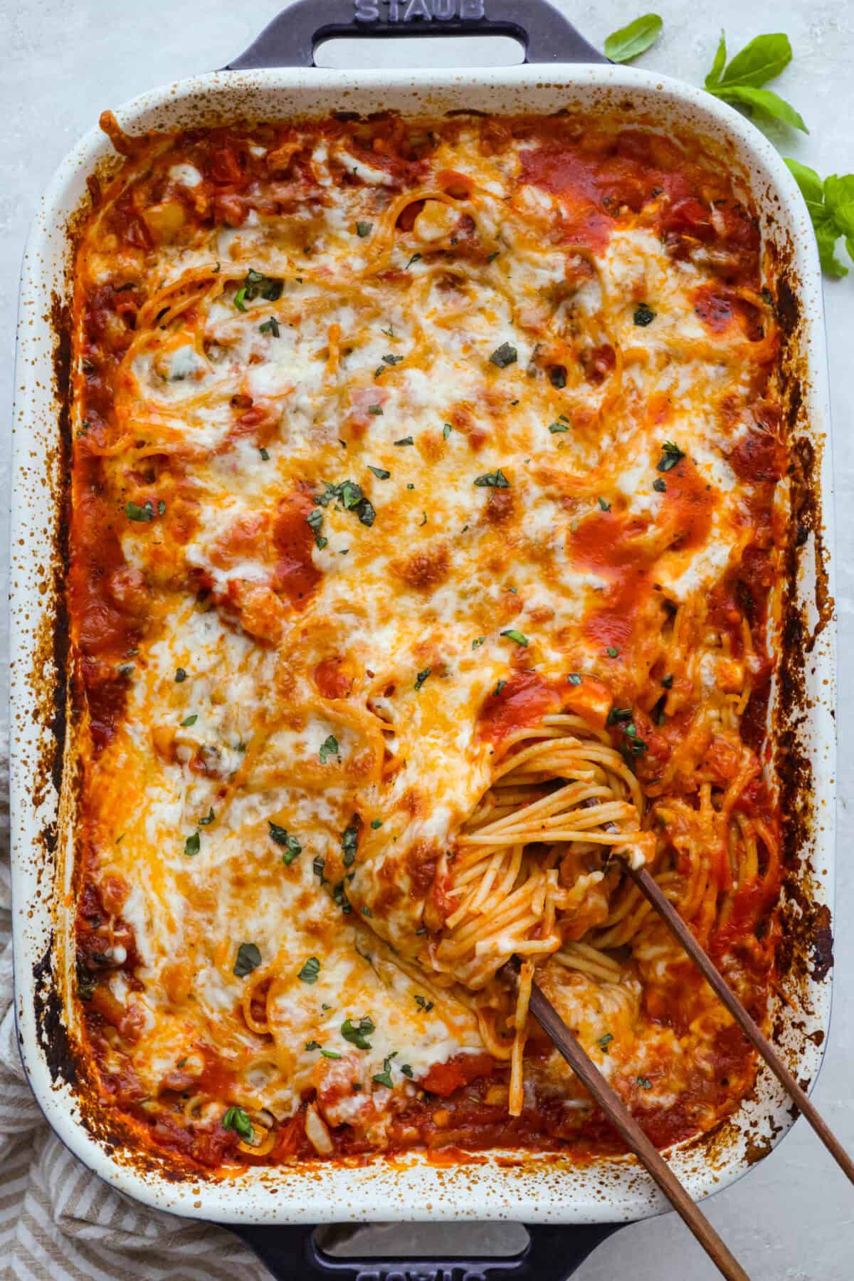 Top down shot of the baked no boil pasta bake with some wooden tongs getting a scoop.