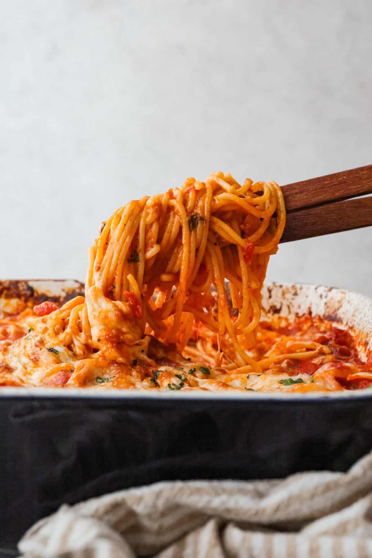 Someone lifting a scoop of the no boil spaghetti bake out of the baking dish. 