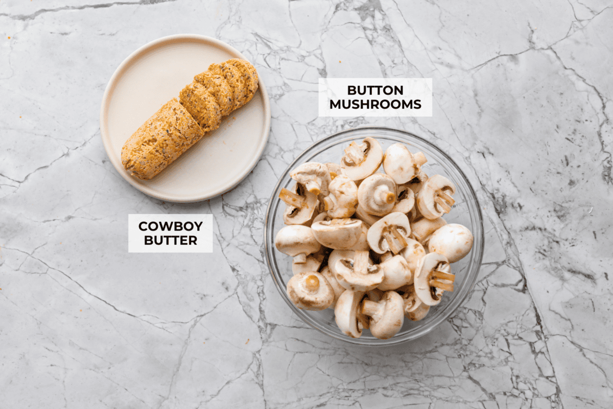 These Cowboy Mushrooms are so easy to make and packed with flavor! Tender, juicy mushrooms are coated in rich, garlicky cowboy butter. Just two ingredients and you've got a side dish that might steal the show! Overhead shot of labeled ingredients.