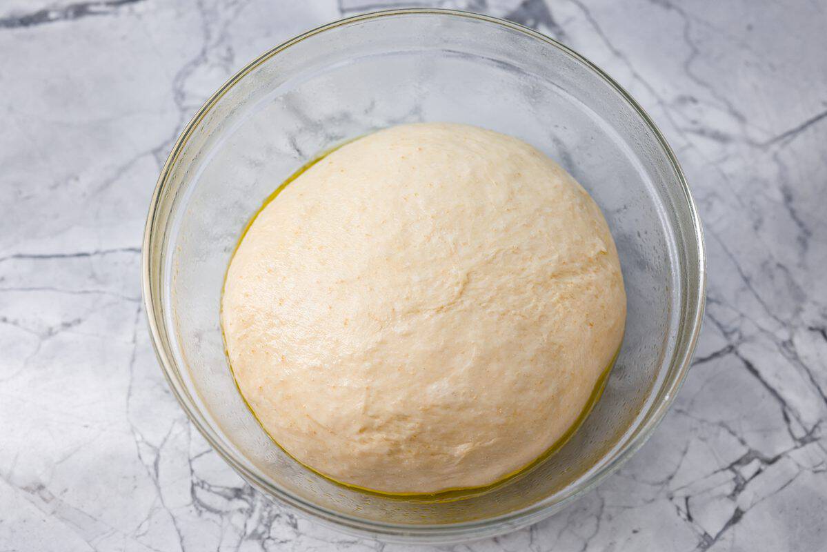 That buttery, garlicky Little Caesars Crazy Bread we all love? You can make it at home, and it's SO good! Soft, fluffy, and covered in Parmesan. Oh, and don't get me started on the garlic butter! Good luck eating just one! Mound of dough covered in olive oil in a glass bowl ready to raise.