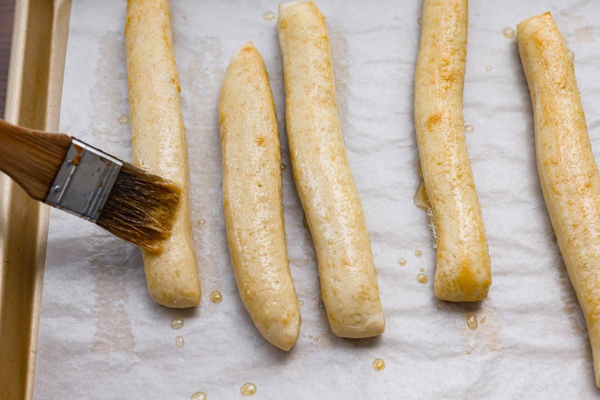That buttery, garlicky Little Caesars Crazy Bread we all love? You can make it at home, and it's SO good! Soft, fluffy, and covered in Parmesan. Oh, and don't get me started on the garlic butter! Good luck eating just one! Someone spreading the melted garlic butter on a breadsticks.