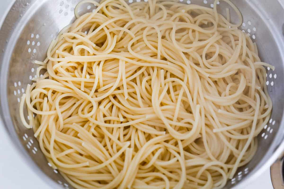 Spaghetti noodles cooked and draining in a colander. 