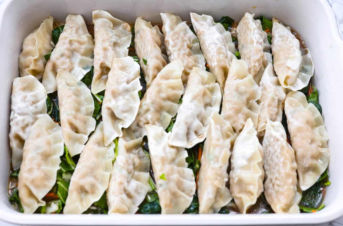 Frozen potstickers added to the top of the veggies, ready to be baked. 