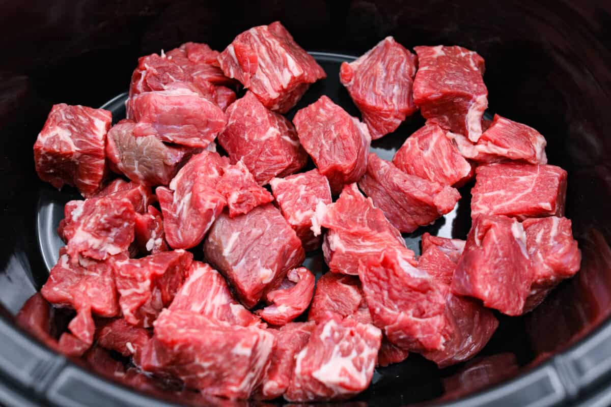 Beef cut into chunks and placed in the slow cooker.