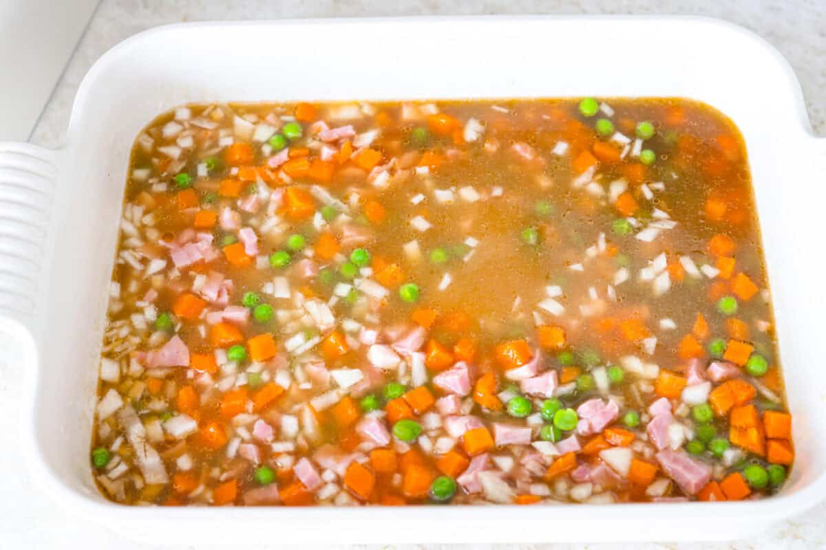 I LOVE fried rice, and my classic fried rice is already so easy, but I’m obsessed with this baked version! Dump everything into one baking dish, pop it in the oven, and dinner is served. It has all that savory fried rice flavor with less work! Veggies, ham, rice, garlic, broth and soy sauce added to a baking dish.