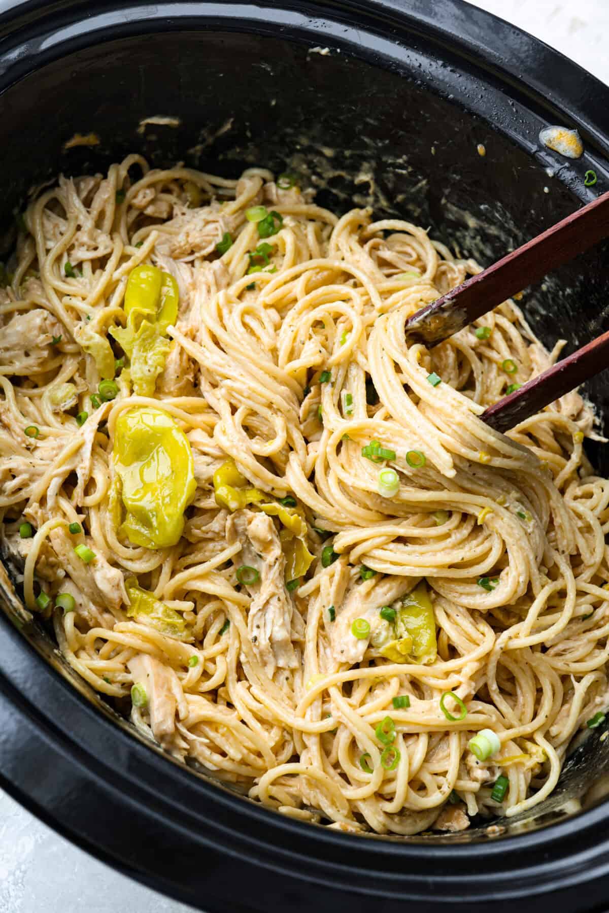 Top down shot of a slow cooker with Mississippi chicken spaghetti all mixed together and ready to serve.