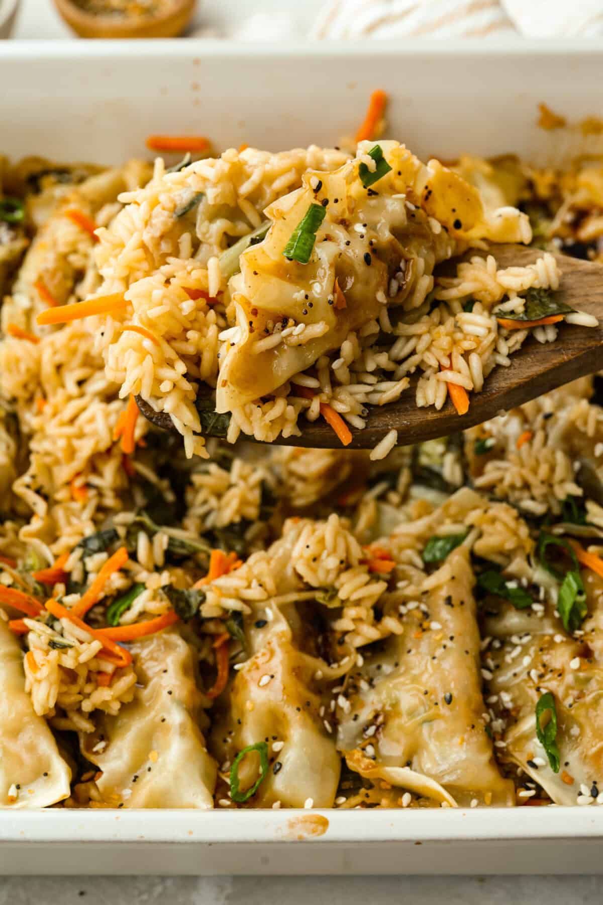 Someone lifting a scoop of potsticker and rice bake out of the baking dish. 