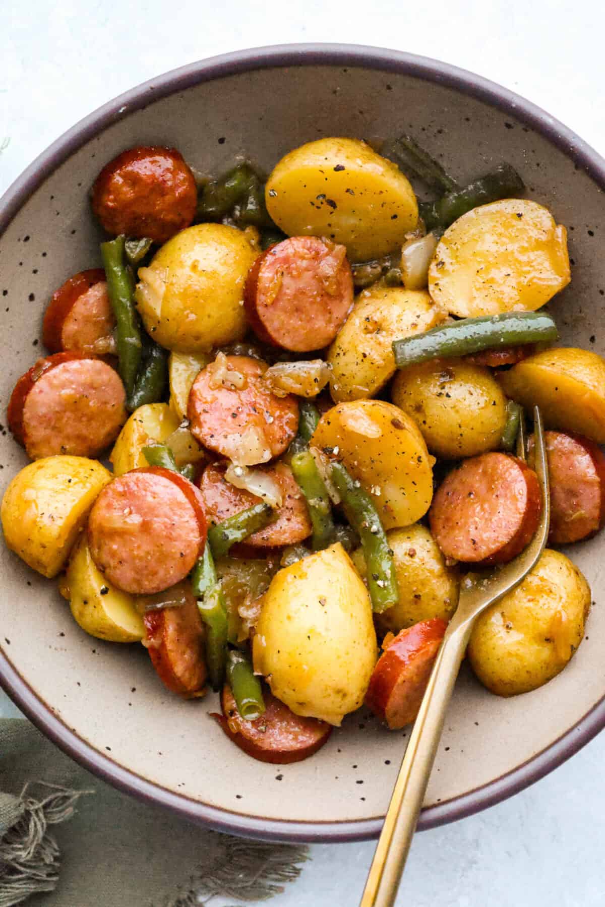 If you haven't tried Swamp Potatoes, you're missing out! This dish is loaded with tender potatoes, smoky sausage, and green beans, all cooked in buttery, savory goodness. Just toss everything in your slow cooker and let it do the work! Bowl of tender swamp potatoes pepper.