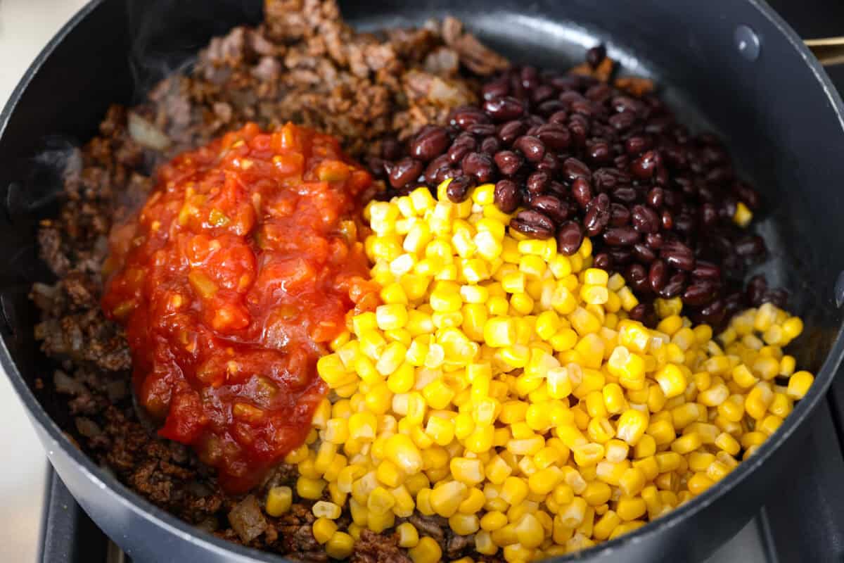 My taco casserole has everything you love about tacos baked into one cheesy, hearty dinner! It's loaded with seasoned ground beef, beans, corn, salsa, and tortilla chips. I love topping mine with sour cream, avocado, and fresh cilantro! Salsa, corn, and black beans added to the skillet.