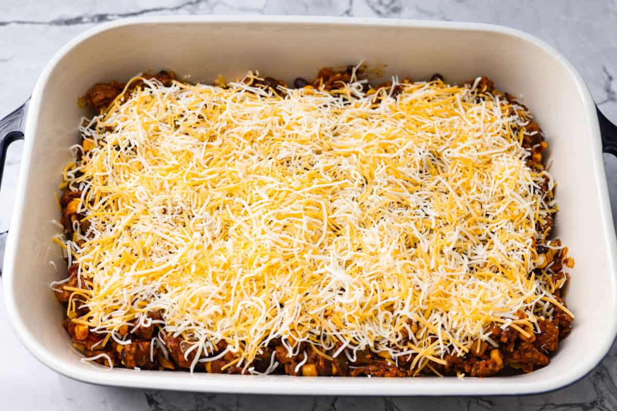 My taco casserole has everything you love about tacos baked into one cheesy, hearty dinner! It's loaded with seasoned ground beef, beans, corn, salsa, and tortilla chips. I love topping mine with sour cream, avocado, and fresh cilantro! Meat mixture added to the top of the chips then topped with cheese.